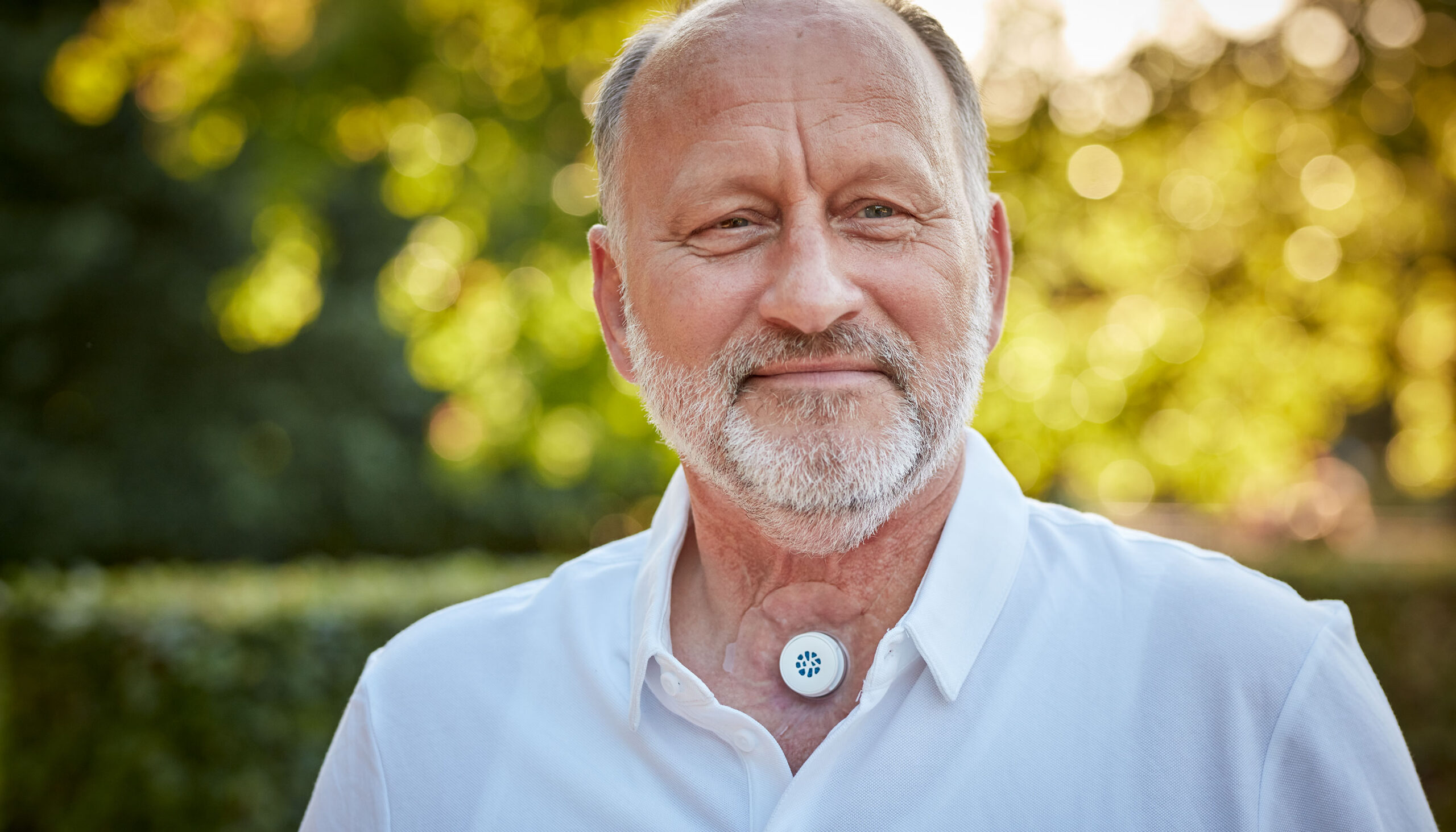 Man with a neck stoma using Provox life energy HME in nature.